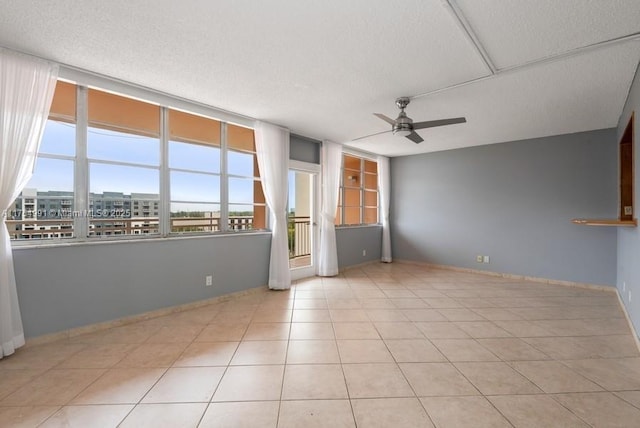 spare room featuring ceiling fan, a textured ceiling, baseboards, and tile patterned flooring