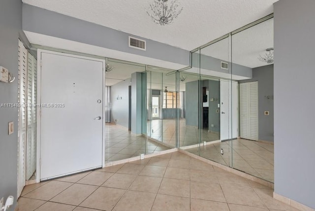 hall featuring visible vents, a textured ceiling, and tile patterned floors