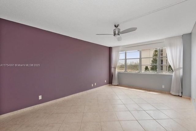 empty room featuring light tile patterned floors, baseboards, and a ceiling fan