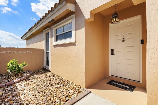 entrance to property featuring a tiled roof and stucco siding