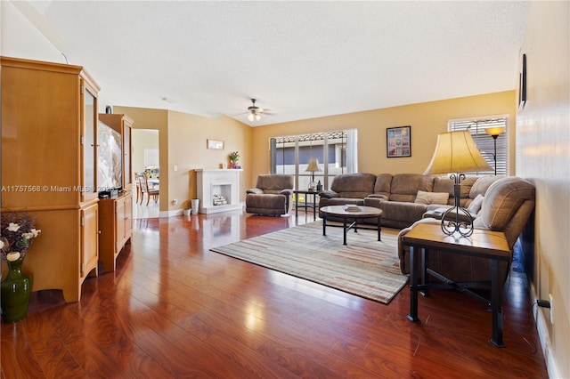 living area featuring vaulted ceiling, a fireplace, dark wood finished floors, and a textured ceiling