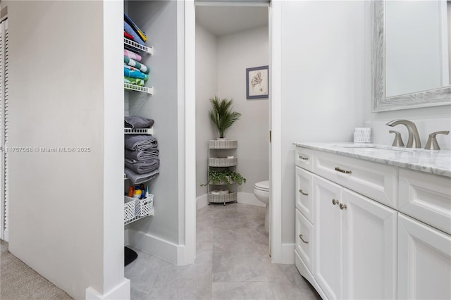 bathroom with baseboards, vanity, and toilet