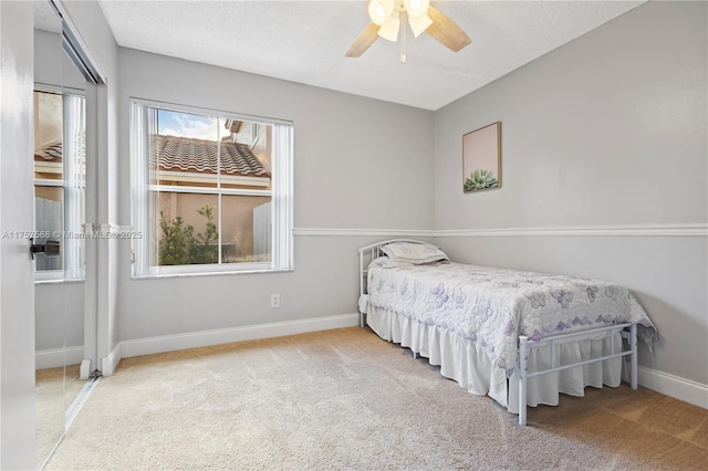 carpeted bedroom with a textured ceiling, a ceiling fan, and baseboards