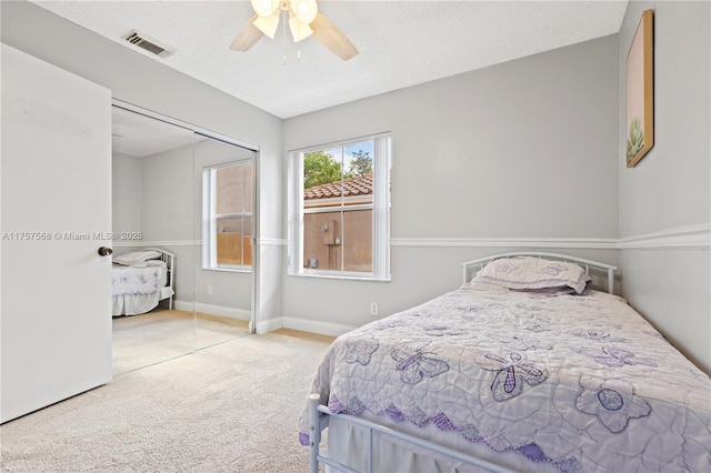 carpeted bedroom featuring baseboards, visible vents, a ceiling fan, a textured ceiling, and a closet