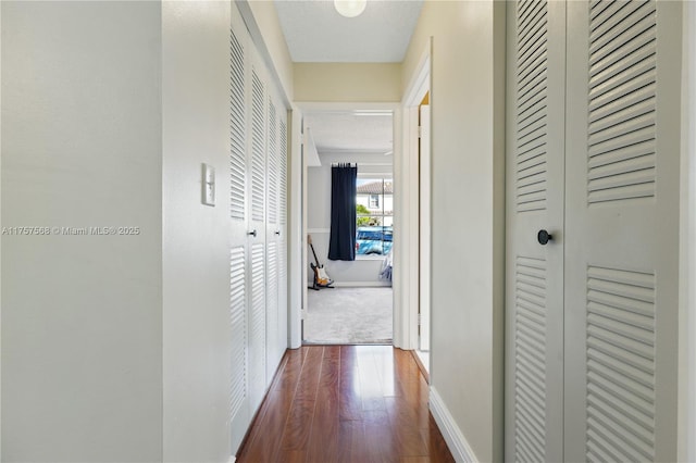 corridor with baseboards and wood finished floors