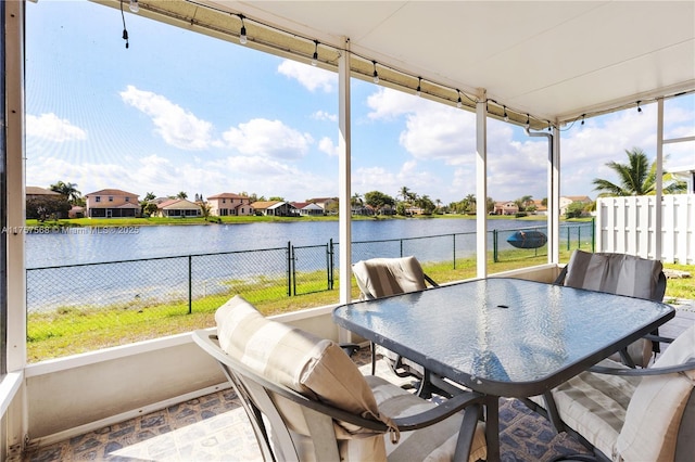 sunroom featuring a water view and a residential view