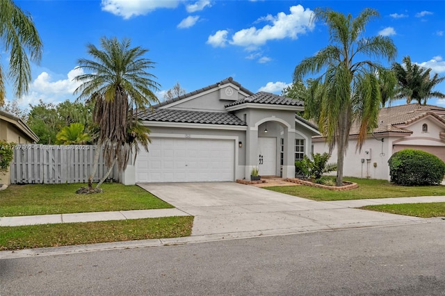 mediterranean / spanish-style house featuring a garage, driveway, fence, a front lawn, and stucco siding