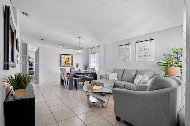 living area with light tile patterned flooring, visible vents, and a textured ceiling