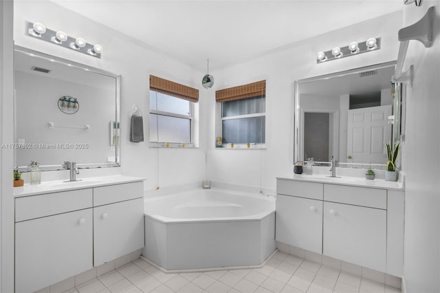 full bathroom with two vanities, a sink, and a bath