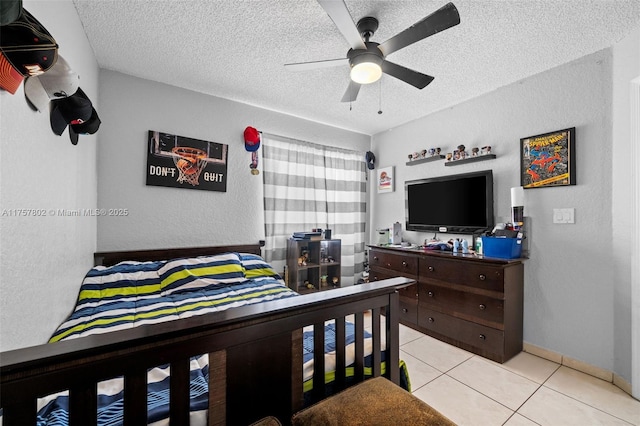 bedroom with light tile patterned floors, baseboards, a textured wall, ceiling fan, and a textured ceiling