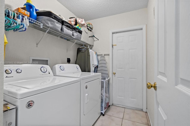 laundry room with light tile patterned floors, laundry area, washer and clothes dryer, and a textured ceiling