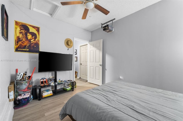 bedroom featuring attic access, ceiling fan, a textured ceiling, and wood finished floors