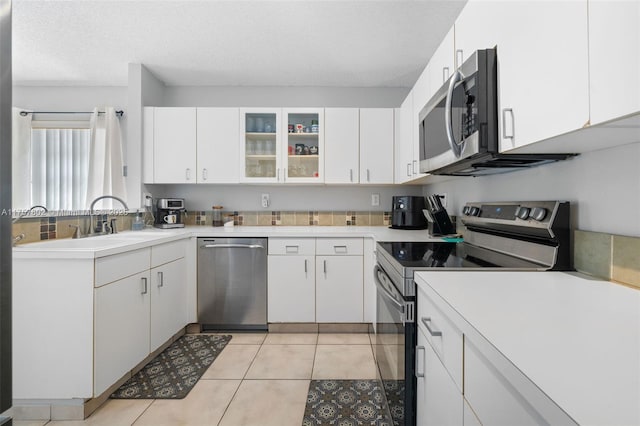 kitchen featuring light tile patterned floors, light countertops, appliances with stainless steel finishes, and white cabinetry