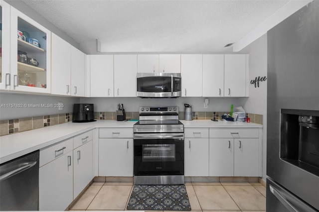 kitchen featuring light countertops, appliances with stainless steel finishes, glass insert cabinets, white cabinetry, and a textured ceiling