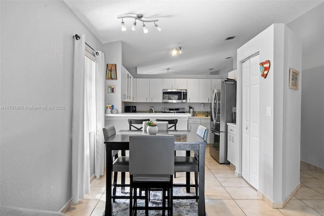 dining space featuring a textured ceiling, baseboards, and light tile patterned floors