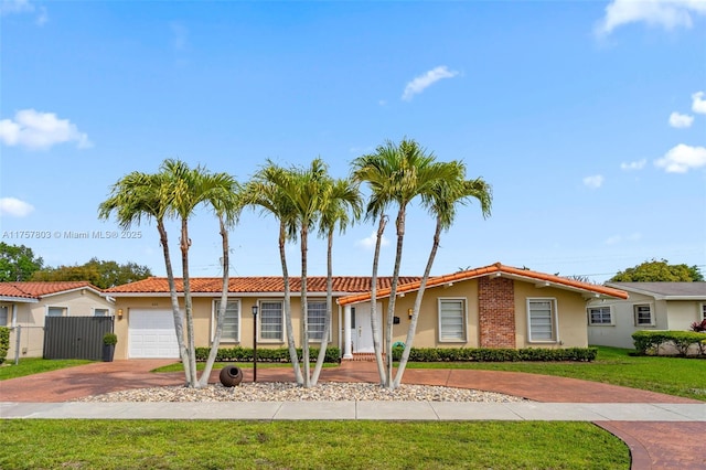 ranch-style home with an attached garage, fence, decorative driveway, stucco siding, and a front yard