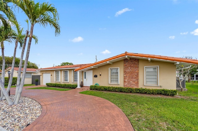 ranch-style home with a front yard, stucco siding, a garage, a tile roof, and decorative driveway