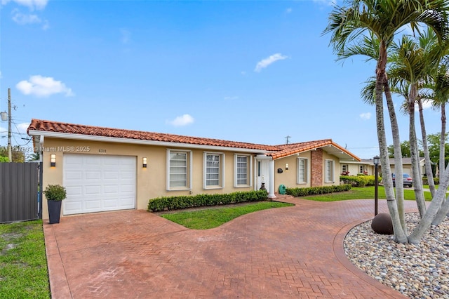 ranch-style house featuring a garage, decorative driveway, a tiled roof, and stucco siding