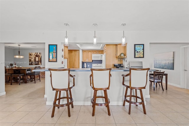 kitchen with white microwave, light tile patterned floors, a peninsula, and a breakfast bar area