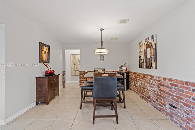 dining area with light tile patterned flooring, baseboards, and brick wall