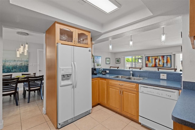 kitchen featuring dark countertops, white appliances, light tile patterned flooring, and a sink