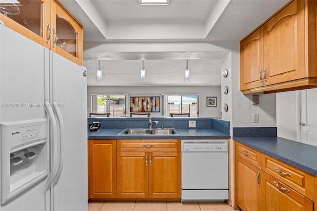 kitchen with white appliances, dark countertops, brown cabinets, and a sink