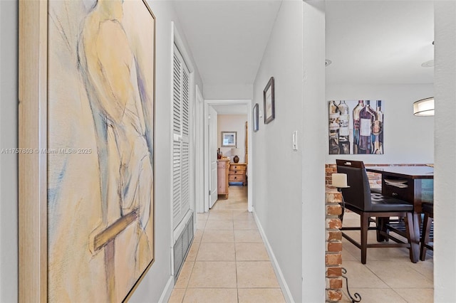 hallway with light tile patterned flooring, visible vents, and baseboards