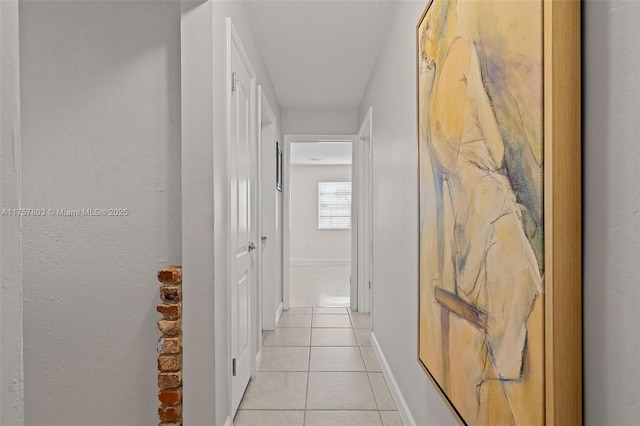 hall featuring light tile patterned floors and baseboards