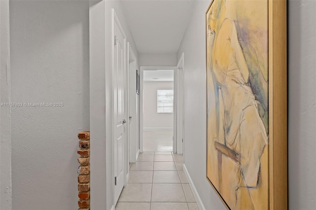hall with light tile patterned flooring and baseboards