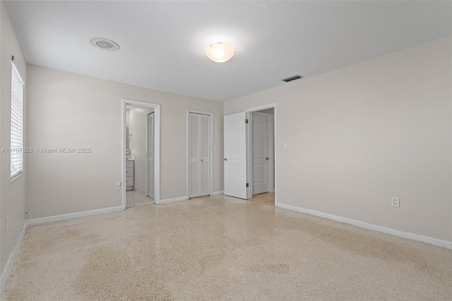 empty room featuring light speckled floor, visible vents, and baseboards