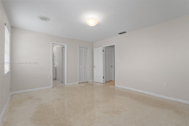 unfurnished bedroom featuring visible vents, light speckled floor, two closets, and baseboards