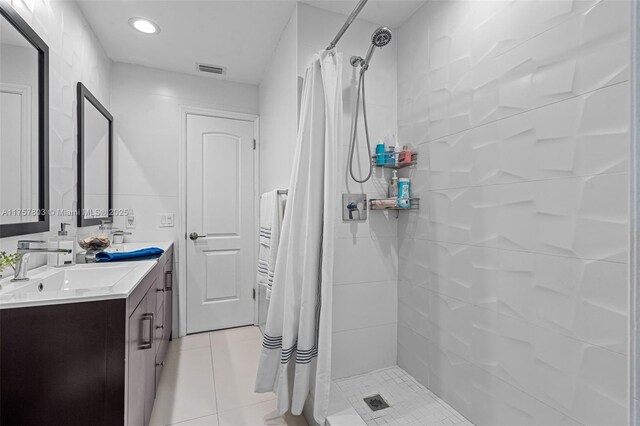 bathroom featuring visible vents, double vanity, a stall shower, tile patterned floors, and a sink