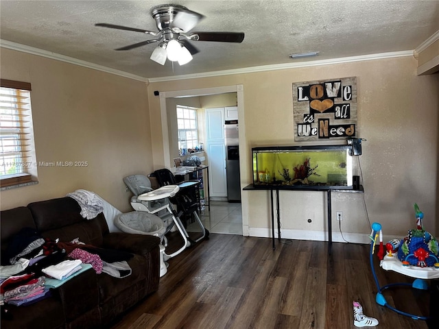 living area with a textured ceiling, ornamental molding, wood finished floors, and a ceiling fan