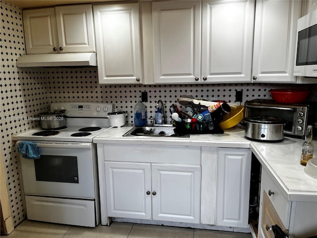 kitchen featuring light countertops, stainless steel microwave, electric range, white cabinetry, and under cabinet range hood