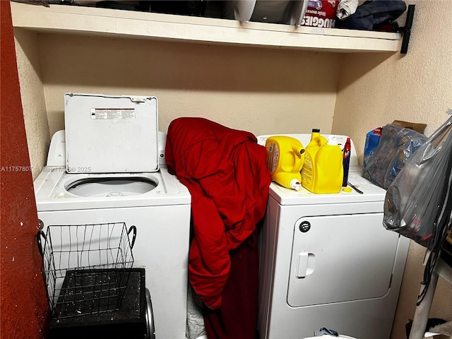 clothes washing area with laundry area, a textured wall, and separate washer and dryer