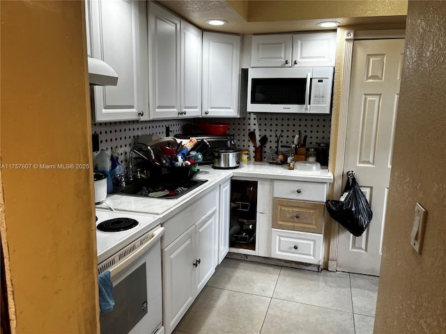 kitchen featuring light countertops, white appliances, white cabinetry, and light tile patterned floors