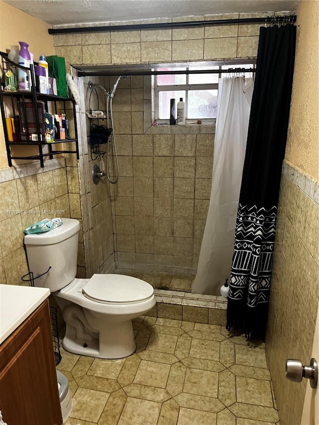 full bath featuring a textured ceiling, toilet, vanity, tile walls, and a shower stall