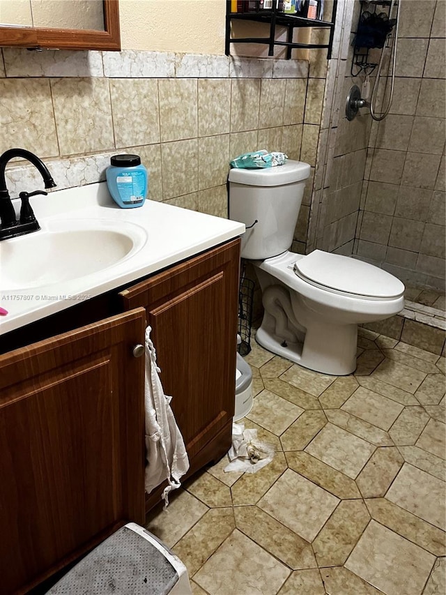 full bathroom with tile walls, a tile shower, vanity, and toilet