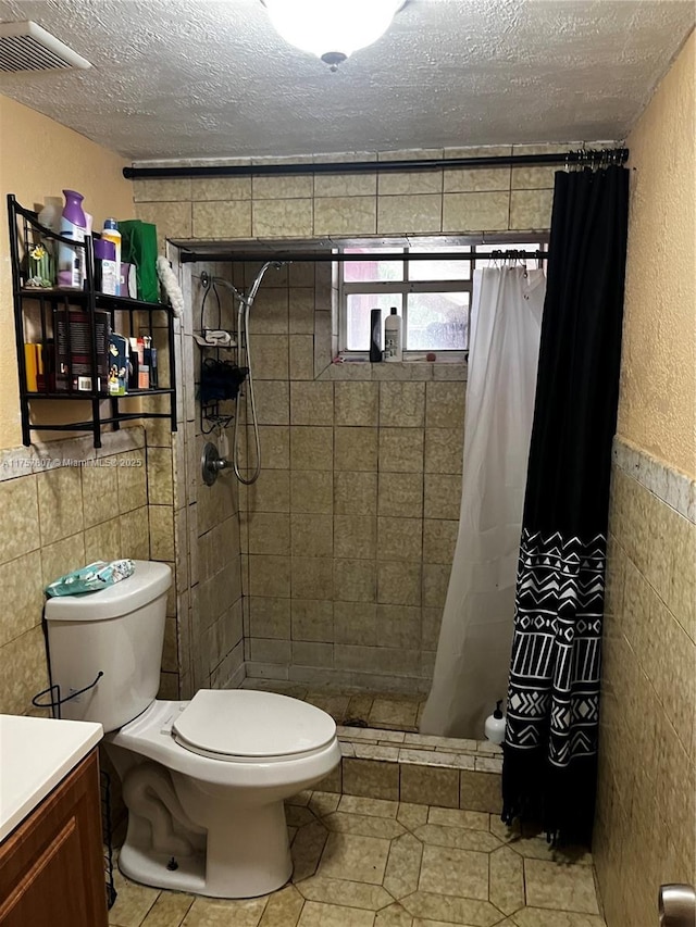 bathroom featuring visible vents, tile walls, toilet, and a textured ceiling