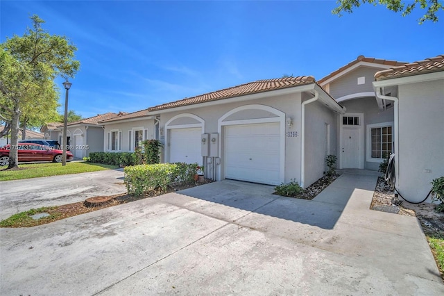 mediterranean / spanish-style house featuring a garage, driveway, a tile roof, and stucco siding