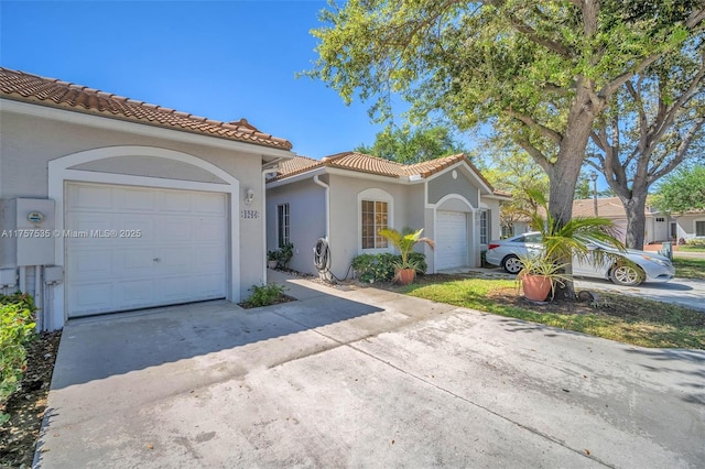 mediterranean / spanish house featuring a garage, a tile roof, concrete driveway, and stucco siding