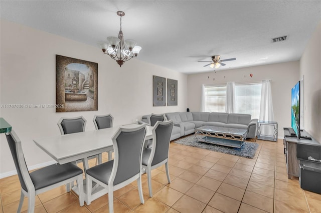 dining area with light tile patterned floors, baseboards, visible vents, a textured ceiling, and ceiling fan with notable chandelier