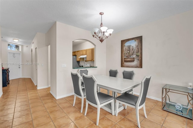 dining space featuring arched walkways, light tile patterned floors, baseboards, and an inviting chandelier