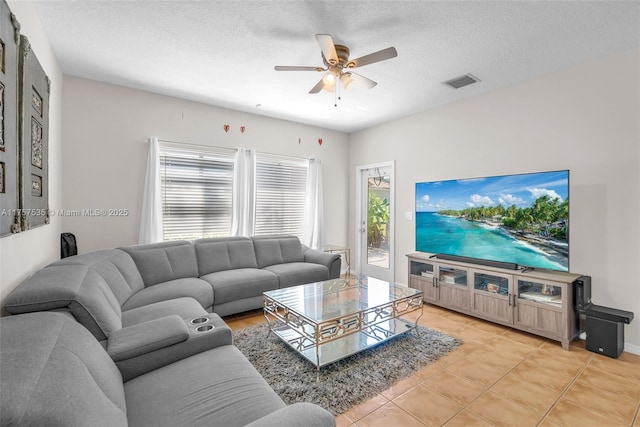 living area featuring a textured ceiling, ceiling fan, light tile patterned floors, and visible vents