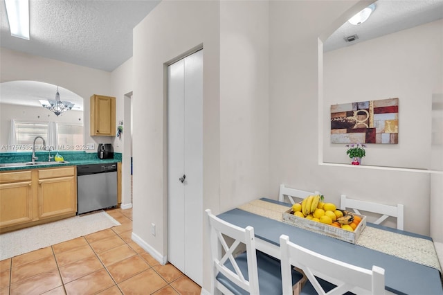 kitchen featuring light tile patterned floors, arched walkways, dishwasher, a textured ceiling, and a sink