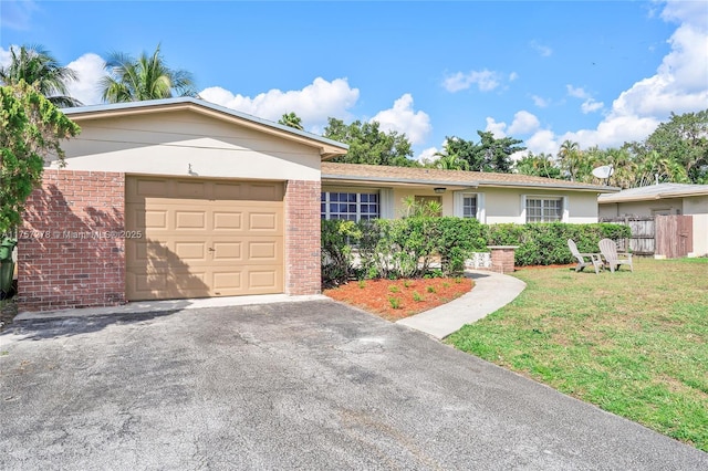 single story home featuring brick siding, a front lawn, an attached garage, and fence