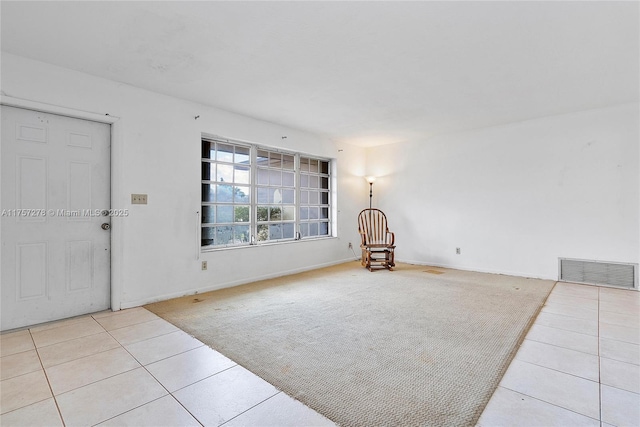 sitting room with carpet floors, visible vents, baseboards, and tile patterned floors