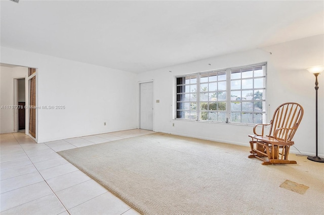 living area with light colored carpet, visible vents, baseboards, and light tile patterned floors