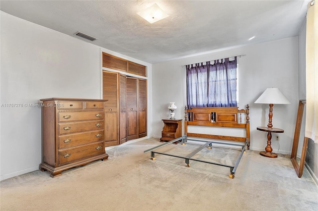 carpeted bedroom featuring a closet, visible vents, a textured ceiling, and baseboards