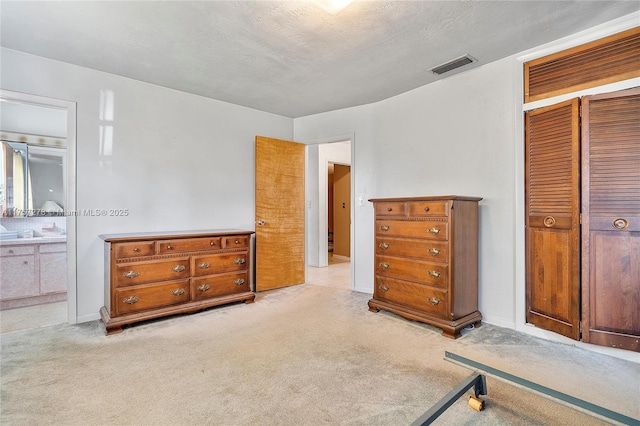 carpeted bedroom featuring a closet, visible vents, and ensuite bath